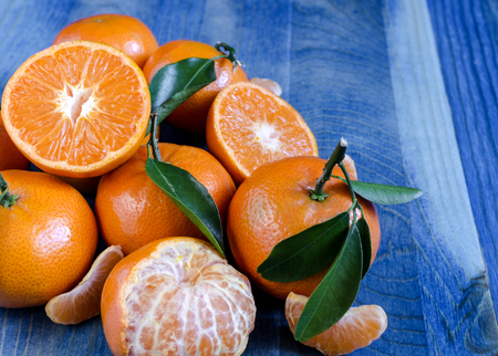 Tangerines with leaves on blue wooden background close-up, copy spaceの写真素材