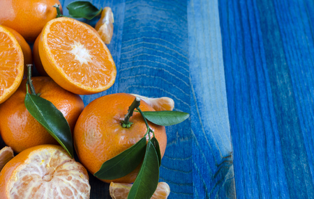 Tangerines with leaves on blue wooden background close-up, copy spaceの写真素材