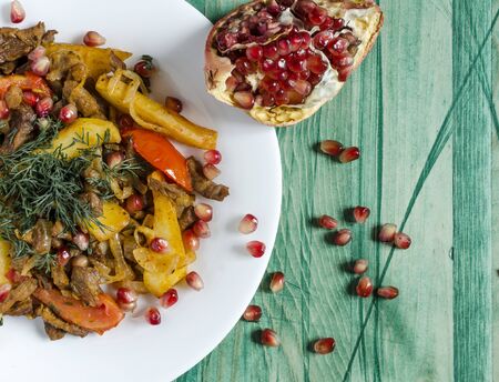 Baked veal with tomatoes decorated with herbs and pomegranate fruits natural color background