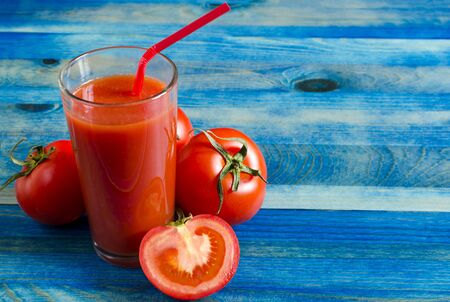 Tomato juice in a clear glass and tomatoes on a wooden background Kopi spaceの写真素材