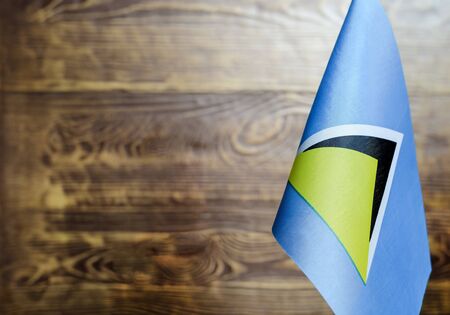 Fragment of the flag of Saint Lucia in the foreground blurred wooden background of the Kopi spaceの写真素材