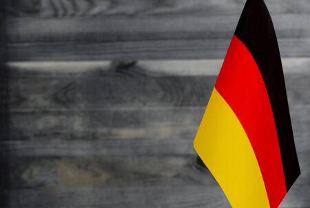 Fragment of the flag of Germany in the foreground blurred wooden background place under the textの写真素材