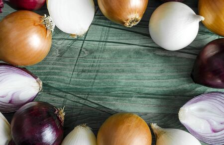 red, white and yellow onions on a wooden background close-up view from aboveの写真素材