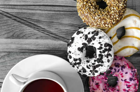 bright donuts in pink, white and brown colors and a white Cup of tea close-up black and white...