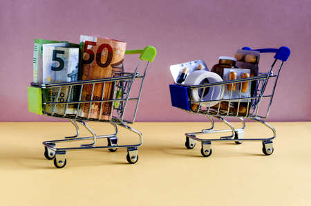 food cart with money bills and food cart with medicines the concept of expensive medicinesの写真素材