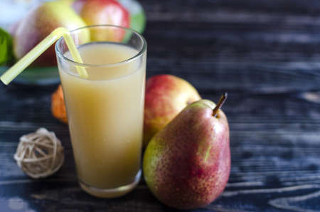 a glass of pear juice and pears on a dark wooden background close upの写真素材