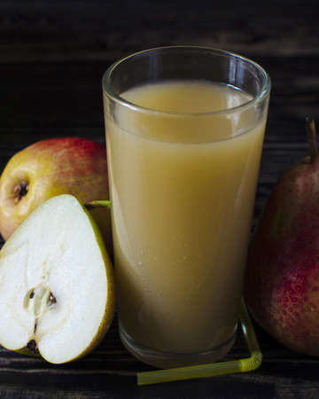 glass of pear juice and pears on a dark background close up verticalの写真素材