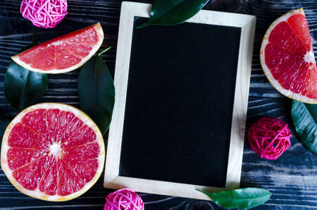 slices of grapefruit green leaves black a sign for the records on the dark wood background flat Lay