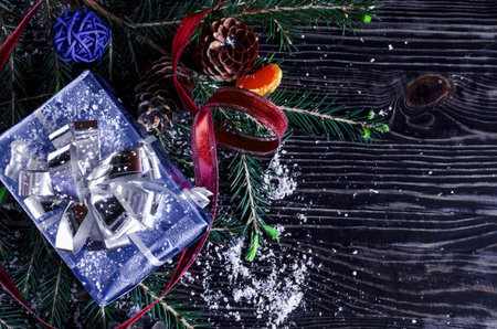 Blue gift box, decorations and fir branches on a dark background Christmas and new year theme.New...