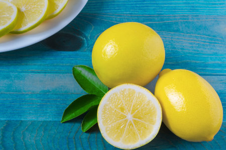bright yellow lemons with leaves and half a lemon close-up on a turquoise background Kopi spaceの写真素材