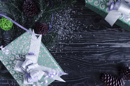 gift boxes in green packaging, decorations and fir branches on a dark background. Christmas and new...