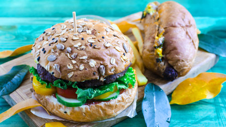 juicy Burger with meat and hot dog with sausage in yellow and green leaves close upの写真素材