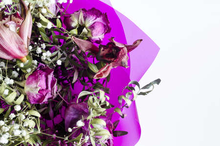 Flower arrangement of red fading flowers orchids and roses in colored paper on a white background close upの写真素材