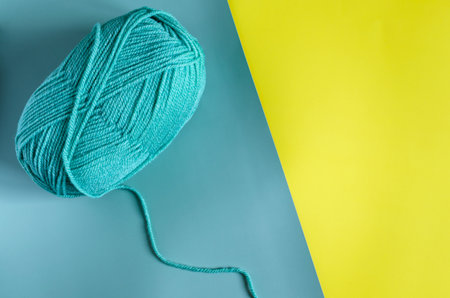 skein of green yarn on a two-tone yellow-green background background top view place for text