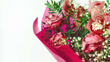 Flower arrangement of red fading flowers orchids and roses in colored paper on a white background close upの写真素材