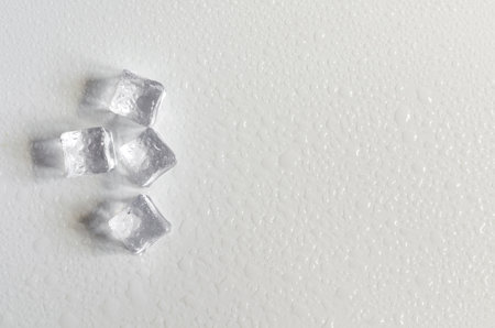 Transparent ice cubes on the light background of the mine space. Background of transparent ice cubes in close-up and water drops on top.の写真素材