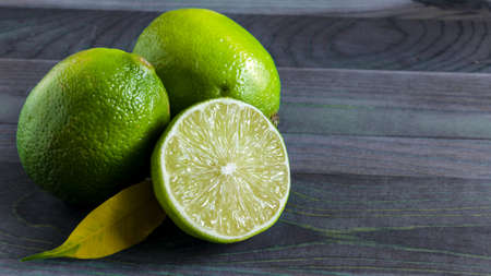 fresh green limes and half a lime on the colored wooden background of the kopi spaceの写真素材