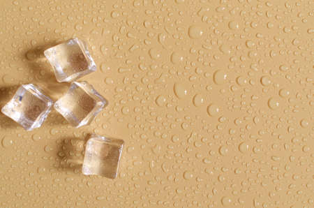 Transparent artificial ice cubes on a light orange background. Background of transparent ice cubes...