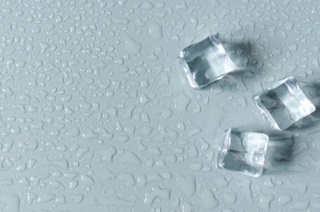 Transparent artificial ice cubes on a light blue background. Background of transparent ice cubes and water drops top view.の写真素材