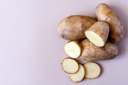 Potato tubers and half a potato on a colored background. Potatoes on a colored background of kopi spaceの写真素材