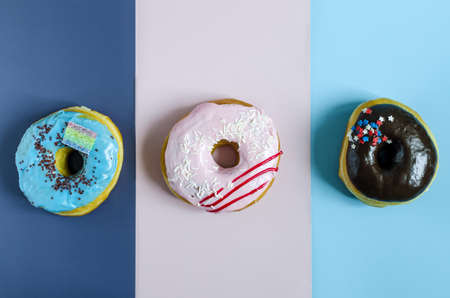 Fresh donuts with colored glaze on a colored background. Multicolored donuts on a three-color background close-upの写真素材