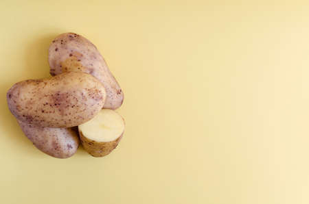 Potato tubers and half a potato on a colored background. Potatoes on a colored background of copy spaceの写真素材