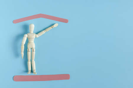 A wooden figure of a man with a raised hand and red frames symbolizing protection on a colored...
