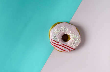 Donuts with pink icing on a colored background. Sweet donut on a two-color divided background of copy spaceの写真素材