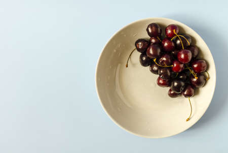 Dark cherry berries in a blue plate close-up.の写真素材