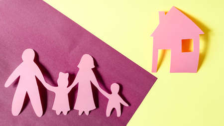 Bright red human figures of people and houses on a colored background. The concept of family relations. Cardboard figures of adults and children close-up mortgage conceptの写真素材
