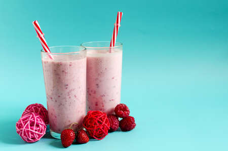 Milkshake with raspberries and red decor on a light background top view. Cocktail of ice cream, milk and berriesの写真素材