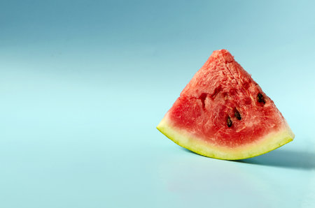 A piece of sweet watermelon on a blue background. A ripe watermelon on a colored background is a...