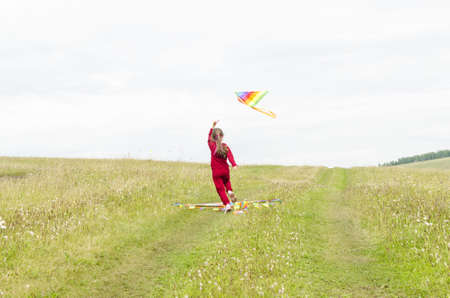 A child running with a kite on the background of grass and sky. A child with a kiteの写真素材