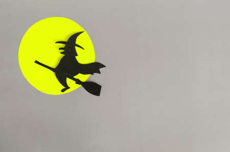 The figure of a black witch on a broomstick against the background of a yellow moon is a place for...