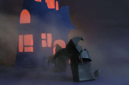 Figures of two dark ghosts with a red glow in the fog against the background of a dark house. Black paper ghosts for the Halloween holidayの写真素材