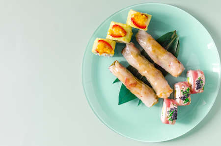 Seafood and vegetable spring rolls and colorful rolls in a blue plate on a light background. Spring rolls Asian cuisineの写真素材