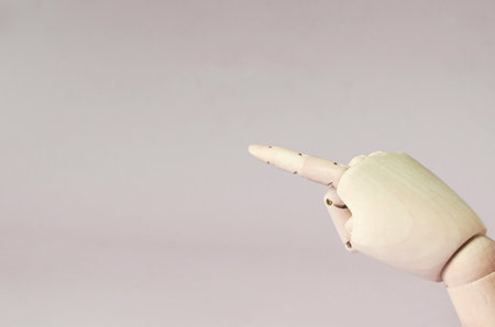 A wooden hand with an outstretched finger pointing to an empty placeの写真素材