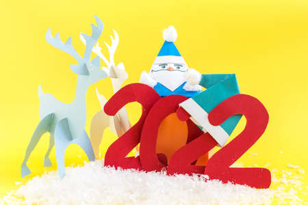 Origami paper deer and the numbers 2022 on a bright yellow background. A bright New Year's card.