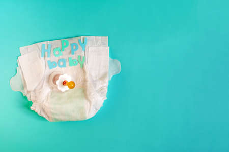 Baby diapers, pacifier and the inscription "happy baby" in colored letters on a light background place for textの写真素材