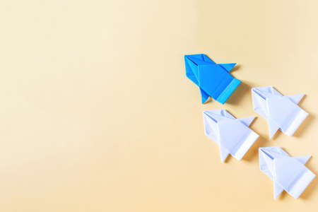 The concept of competition and rivalry. A blue paper car competes with nondescript white cars on a colored backgroundの写真素材