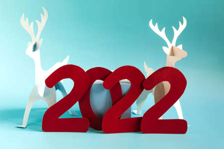 Handmade on the theme of the new year origami paper deer and the numbers 2022 on a bright blue background. A bright New Year's card.の写真素材