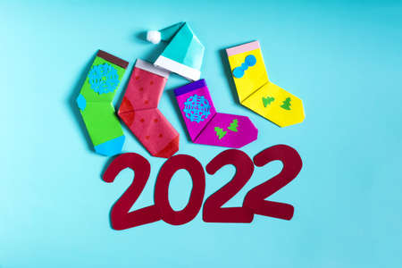 Bright Christmas decor, colored socks, a Christmas hat and the numbers 2022 on a colored background top view.の写真素材