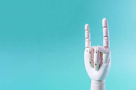 A wooden hand with raised index finger and little finger on a blue background of the space mine. Conceptual hand gestureの写真素材