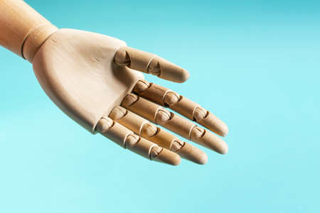 The open palm of a wooden mannequin on a blue background. The concept of openness and honesty, an...