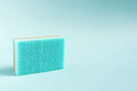 Colored porous sponge for cleaning and washing dishes close-up on a blue background copy space