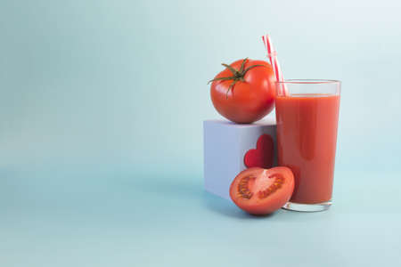 The concept of a positive attitude to tomato juice. Tomato juice, podium with a heart and half a tomato on a light backgroundの写真素材