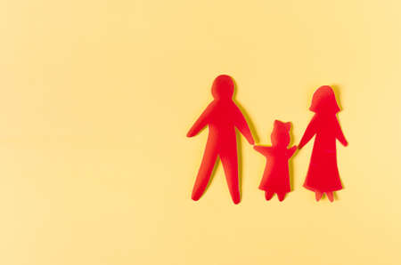 Cardboard figures of two adults and a child on a colored background of copy space. The concept of family relations.の写真素材