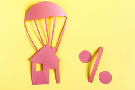 Abstract painting cardboard house and percent sign on a yellow background copy spaceの写真素材