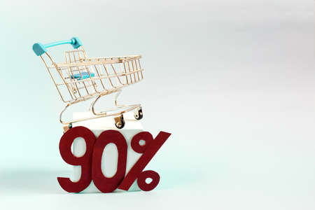 Advertising layout with a 90% discount. The consumer basket and 90% figures on a blue background copy the space.の写真素材