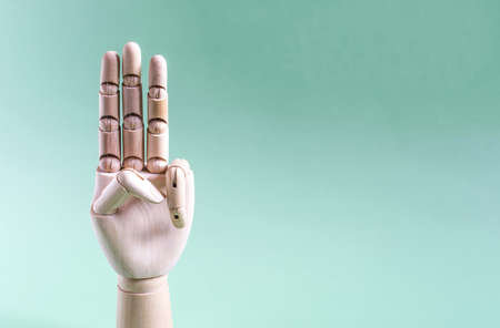 Wooden handle with three raised fingers on a blue background. Conceptual gesture number threeの写真素材